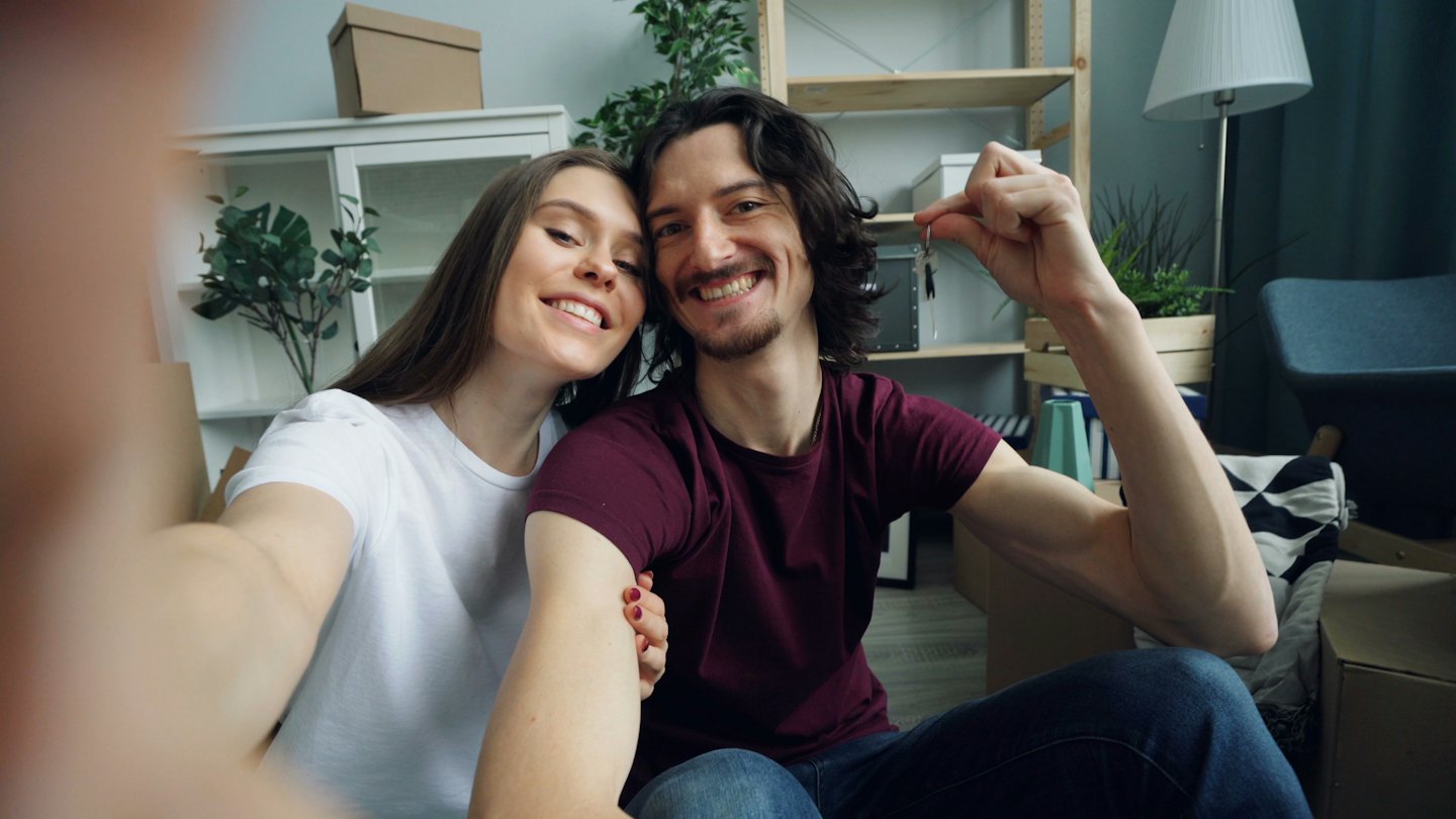 Couple smiles taking a selfie with new house keys.